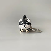 Single hand-carved dog keychain with a close-up of its front, highlighting its black and white paint and big eyes